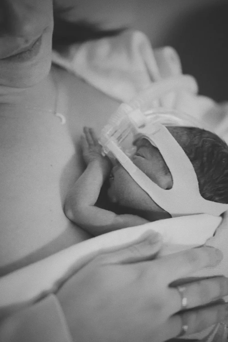 Maman appliquant la méthode kangourou pour apaiser son bébé prématuré en service de soins intensifs.